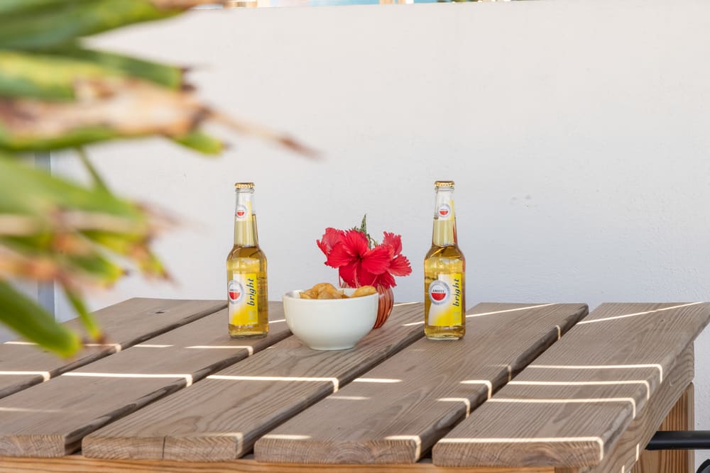 Cold local beers and a hibiscus flower on a sunny terrace table